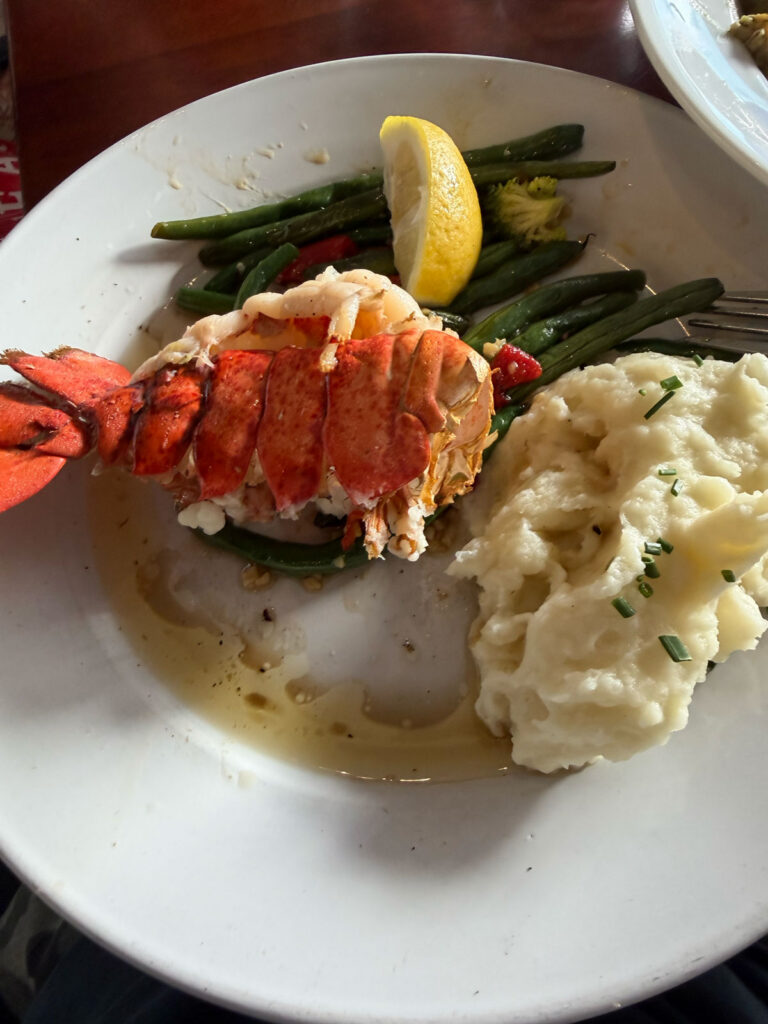 A lobster tail dinner with mashed potatoes and green beans