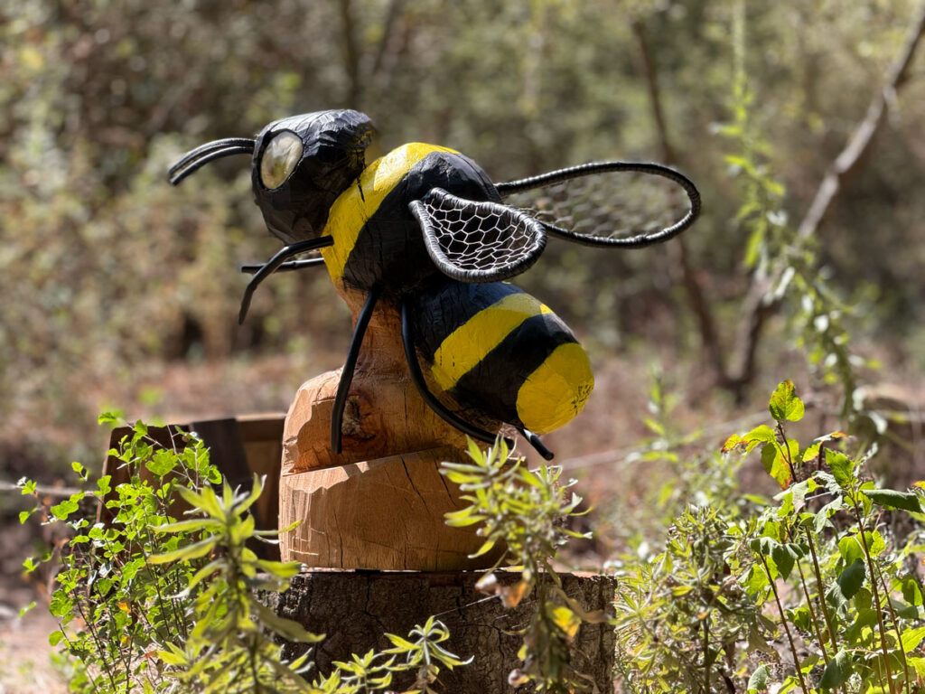A carved bee sculpture perched on a tree stump