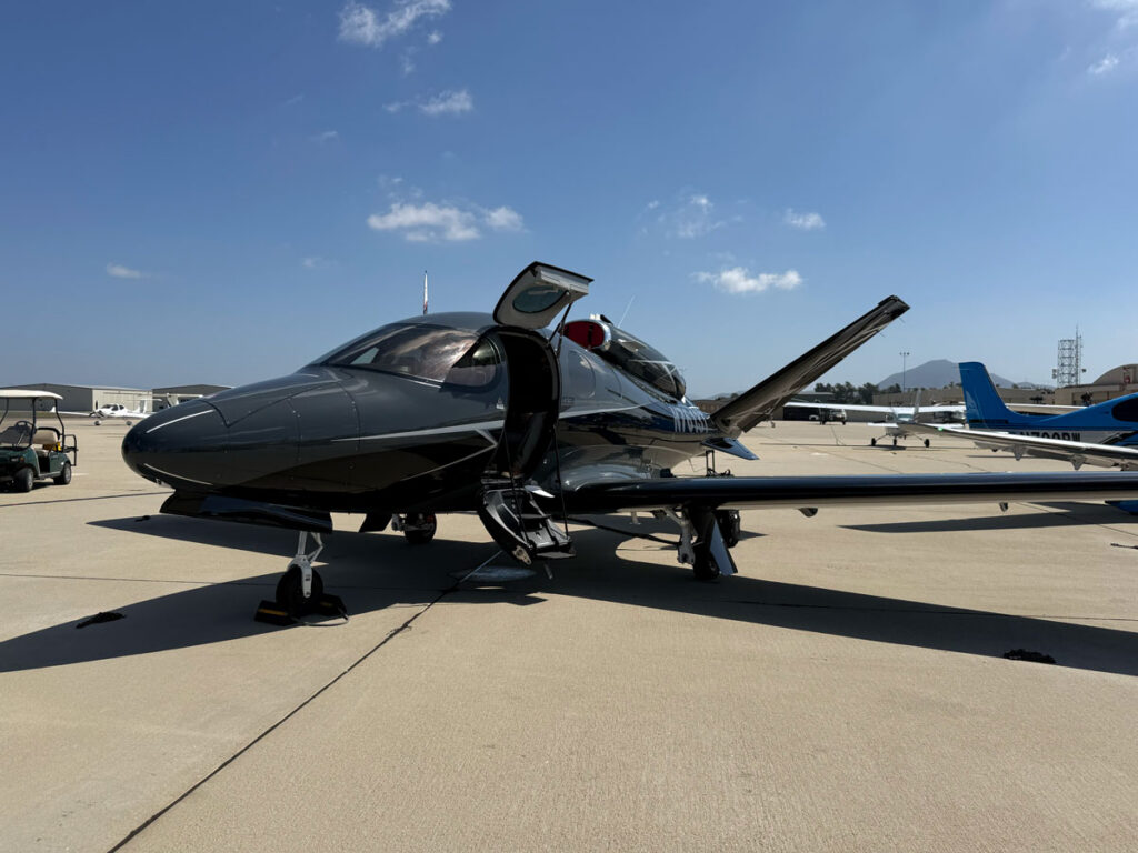 A dark Cirrus Vision Jet with its canopy open