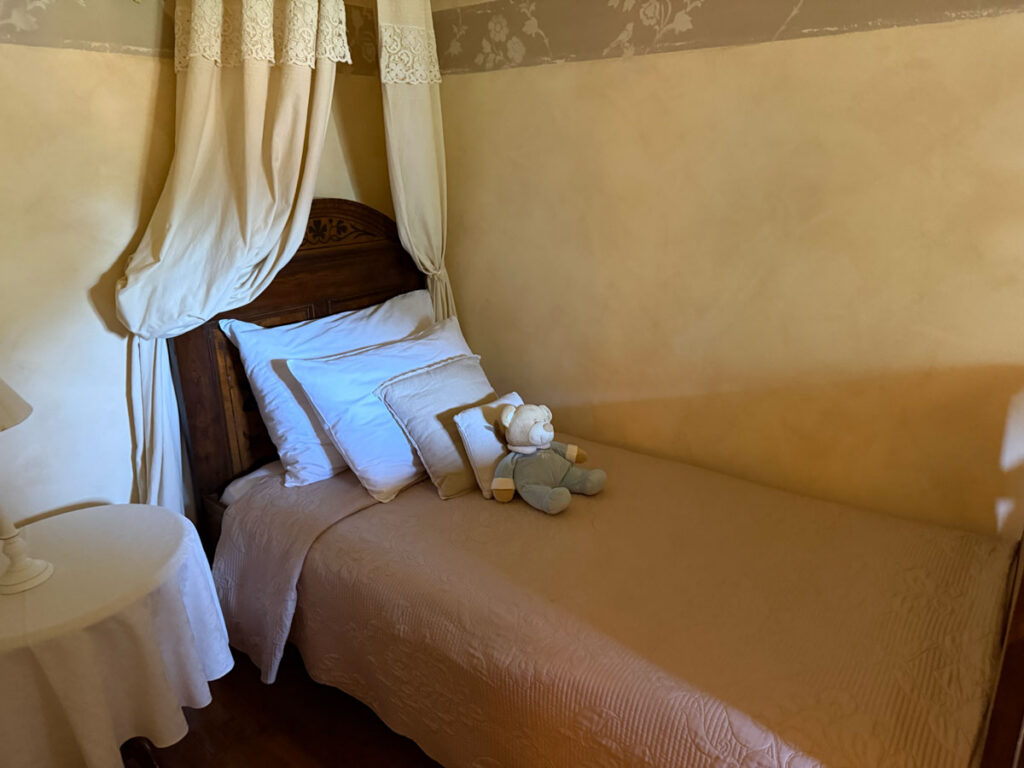 One of the guest rooms, with its carved antique headboard and hand-draped curtains