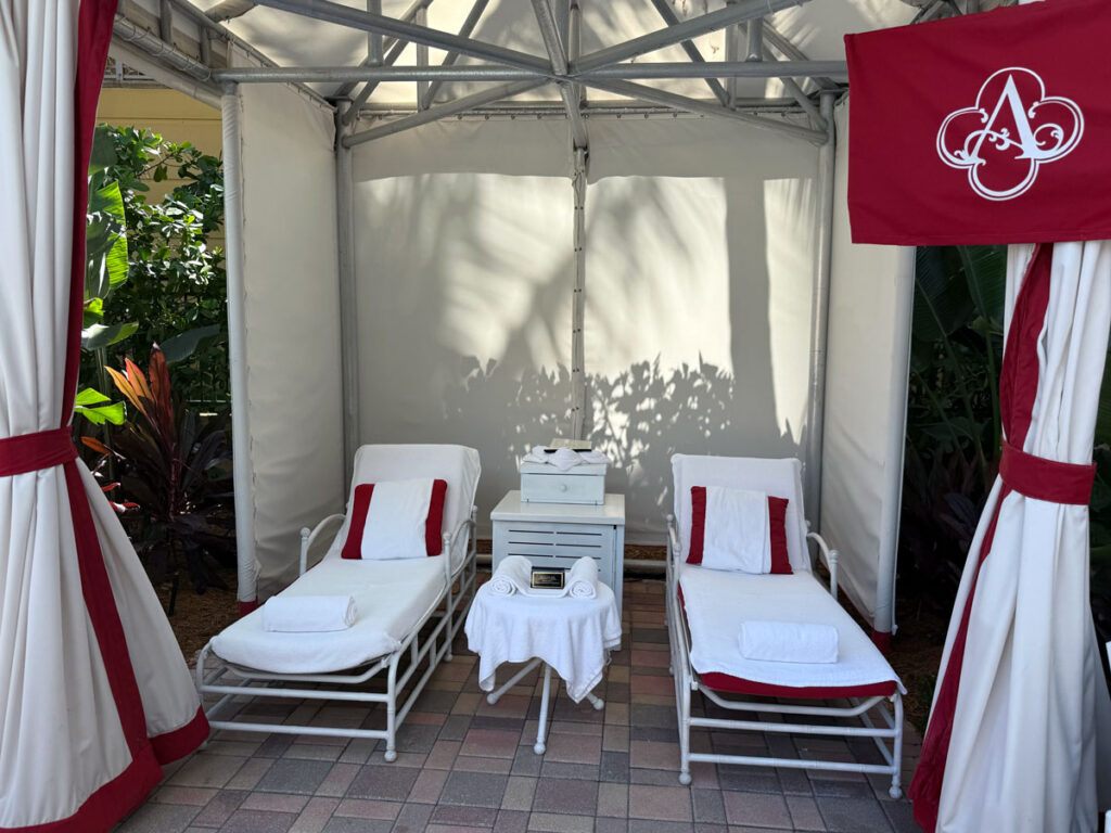 A shaded beach cabana with two lounge chairs - Acqualina Resort & Residences