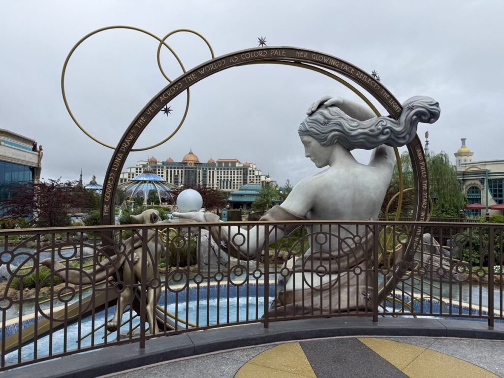 A large white statue reclining inside a gold ring in Celestial Park