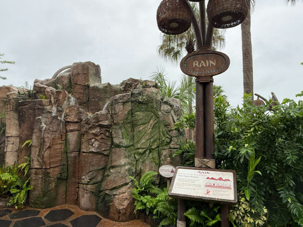 A Rain station sign on a lantern post beside a rock formation